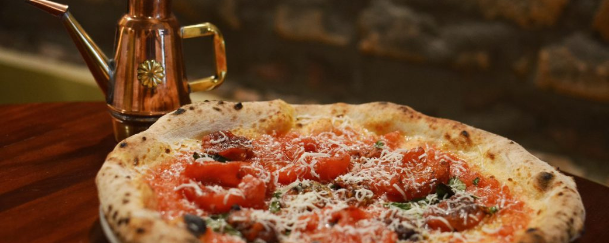 Pizza em SP com recheio de tomates e queijo ralado em cima. 