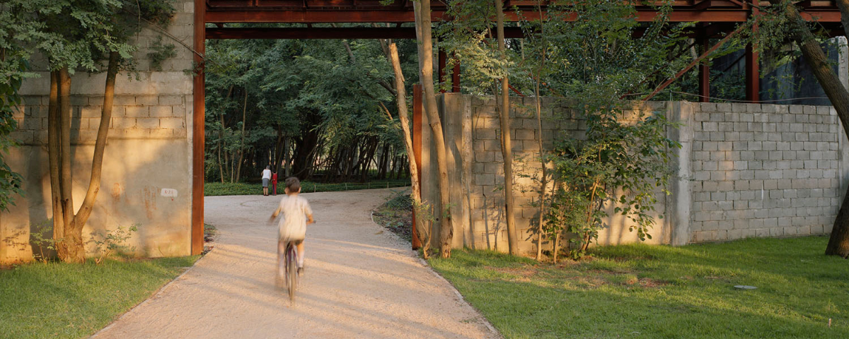 Criança de costas andando de bicicleta na entrada no Parque da Juventude. 