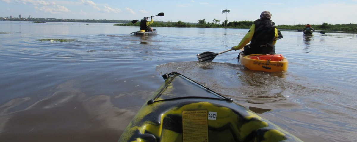 Três pessoas andando de caiaque em um lago. 