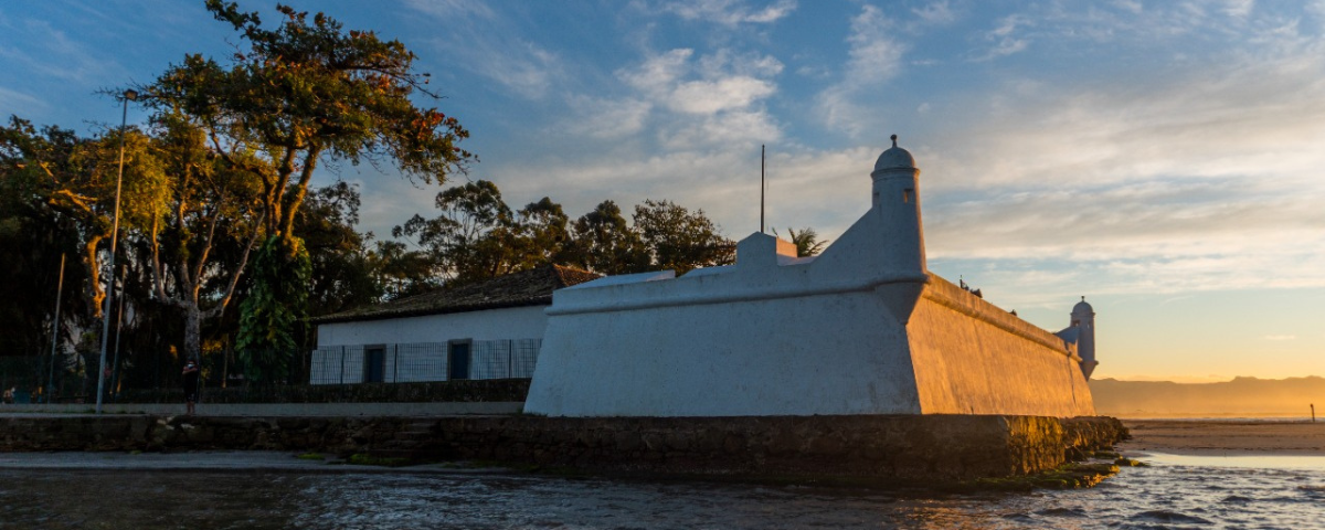 Forte São João é branco e fica na beira do mar. Visitá-lo é um dos passeios em Bertioga.